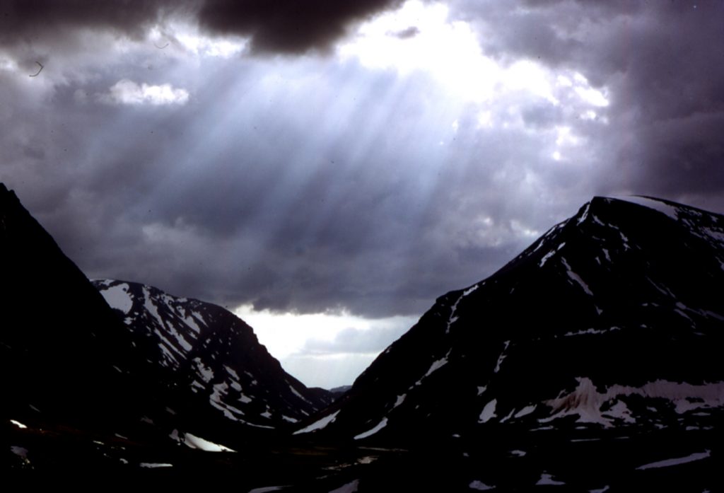 Fjäll med ljus som silar genom molnen